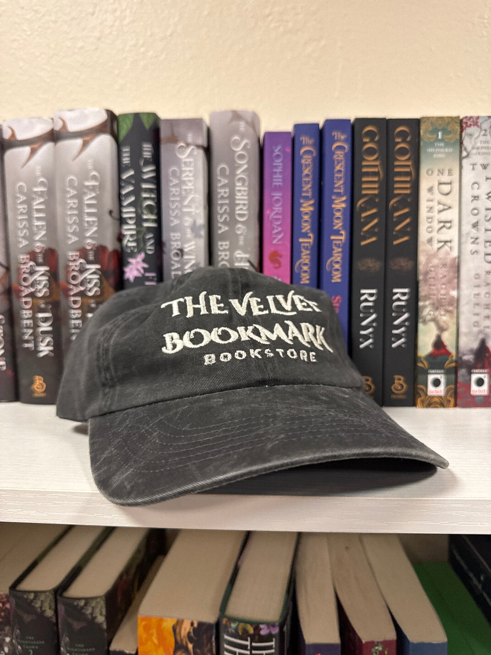 Stack of books with a 'The Velvet Bookmark Bookstore' cap on top