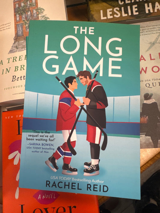 Book titled 'The Long Game' by Rachel Reid on a surface with other books.