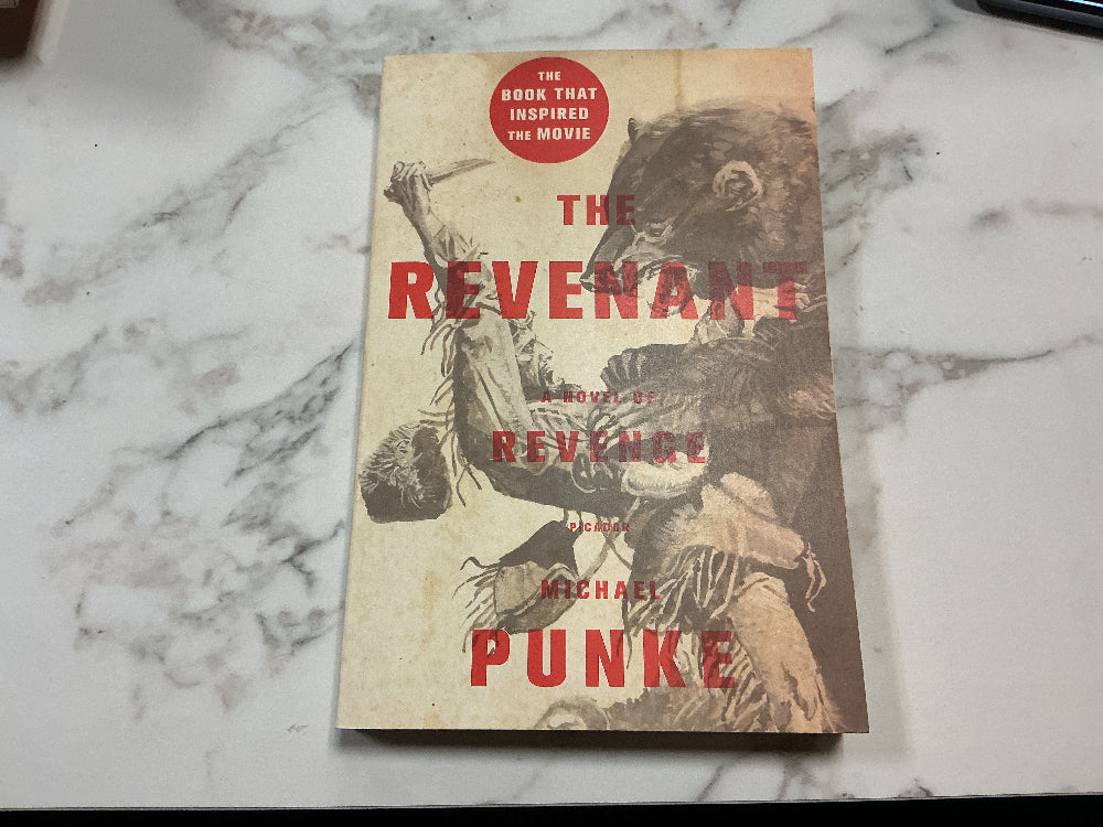 Book titled 'The Revenant' by Michael Punke on a marble surface