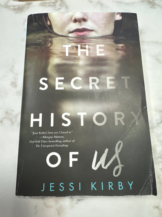 Book titled 'The Secret History of Us' by Jessi Kirby on a marble surface