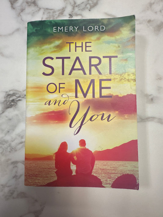 Book titled 'The Start of Me and You' by Emery Lord on a marble surface