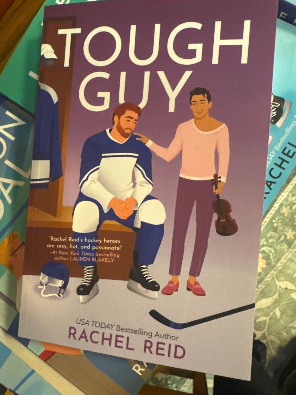Book titled 'Tough Guy' by Rachel Reid on a surface with other books.