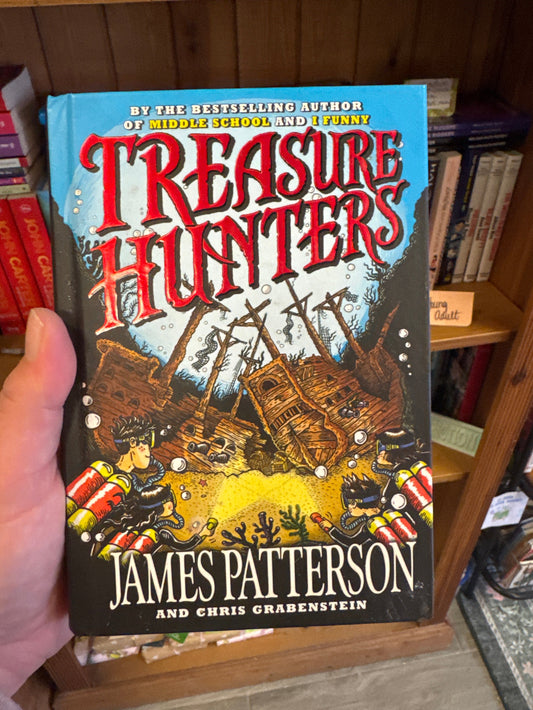 Book titled 'Treasure Hunter' by James Patterson held in front of a bookshelf.