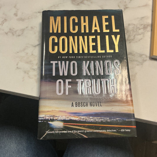 Book titled 'Two Kinds of Truth' by Michael Connelly on a marble surface.