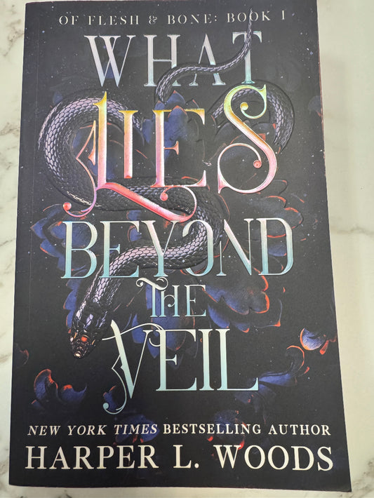 Book cover of 'What Lies Beyond the Veil' by Harper L. Woods on a marble surface