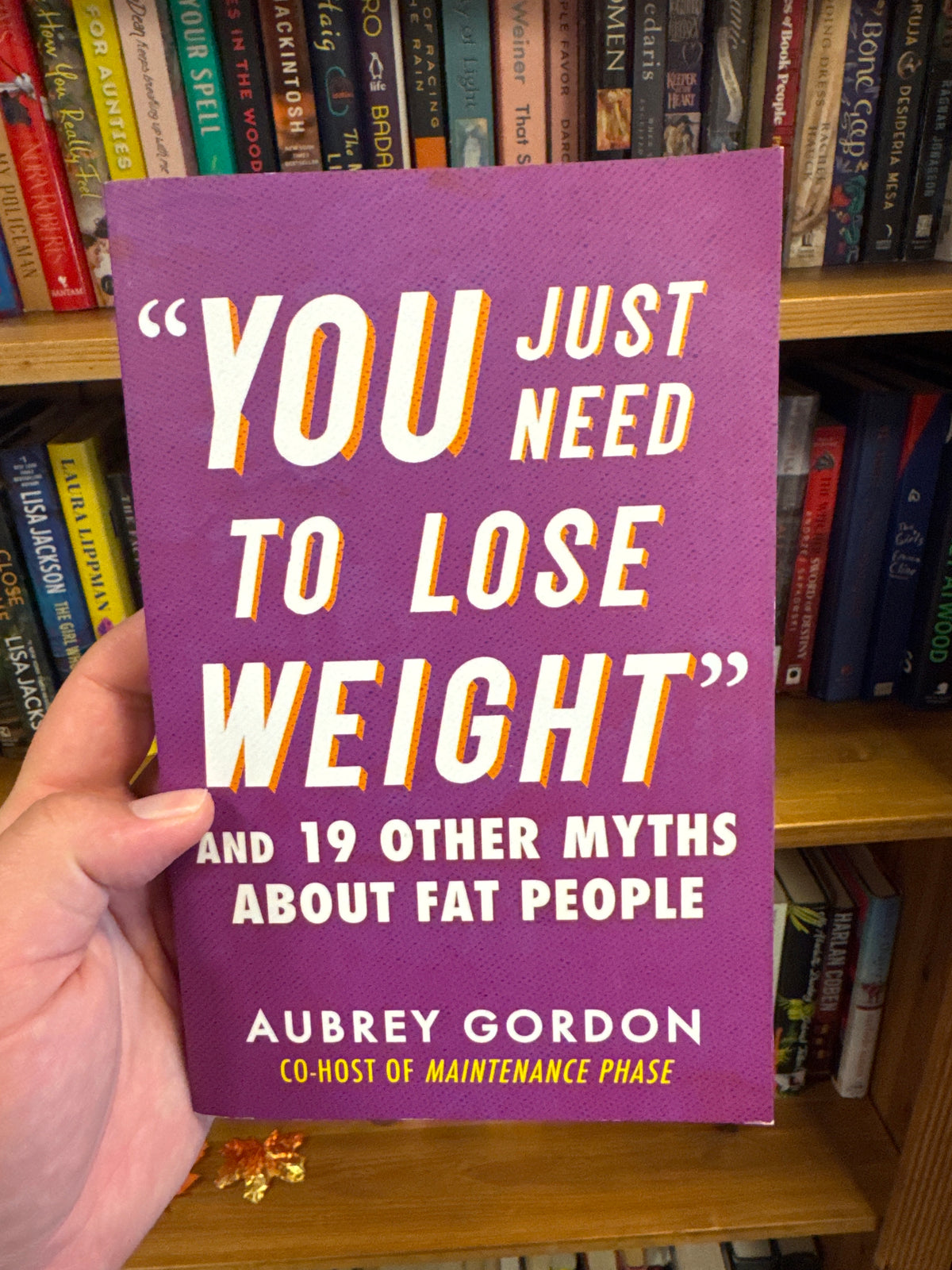 You Just Need To Lose Weight hardcover book by Aubrey Gordon on wooden bookshelf