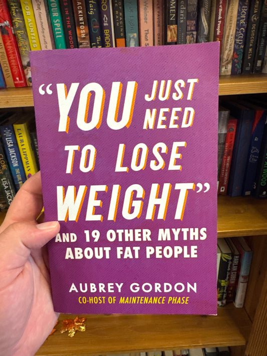 You Just Need To Lose Weight hardcover book by Aubrey Gordon on wooden bookshelf